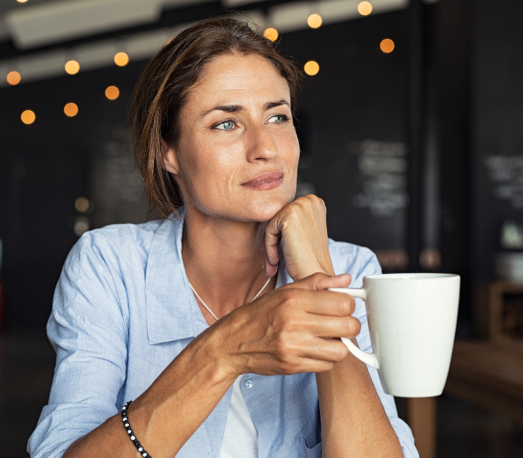 Thoughtful Mature Woman Sitting In Cafeteria Holding Coffee Mug While