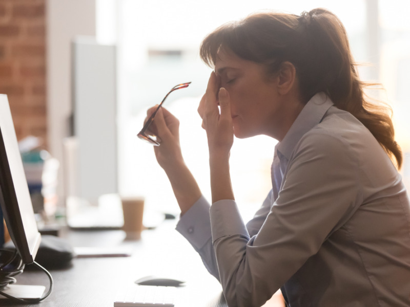 Exhausted Female Worker Sit At Office Desk Take Off Glasses