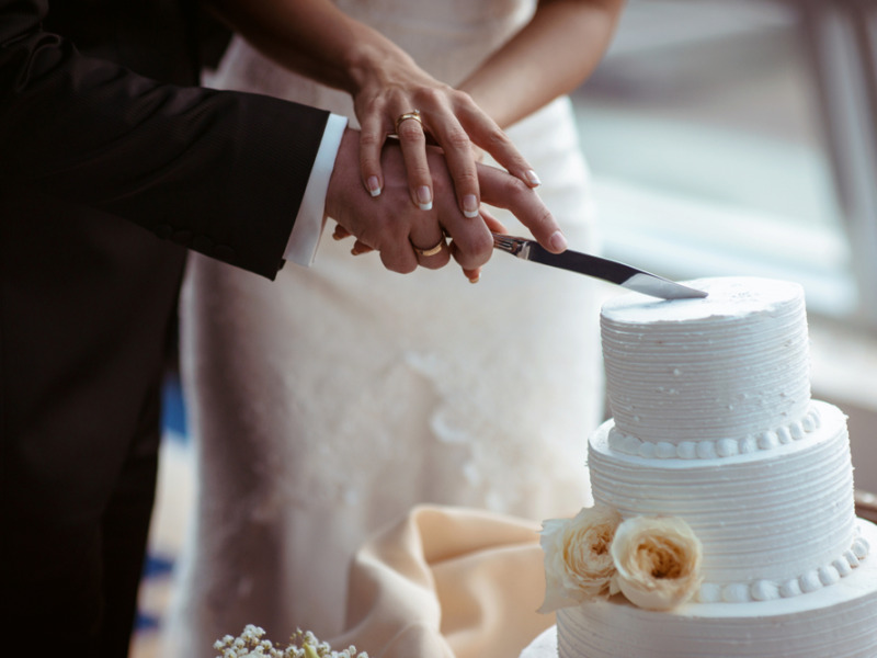 A Bride And A Groom Is Cutting Their Wedding Cake.