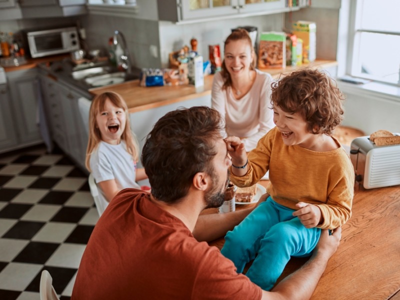Young Family Having Breakfast Together And Being Messy In The